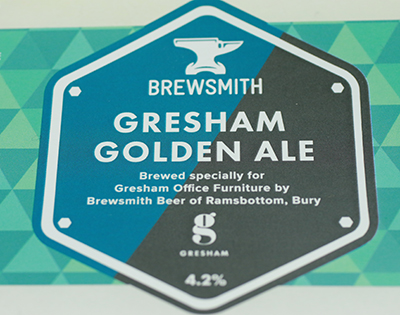 Example of a beverage label - Brewsmith Gresham Golden Ale label, featuring the product name, brewed for Gresham Office Furniture by Brewsmith Beer of Ramsbottom, Bury, with a 4.2% ABV.