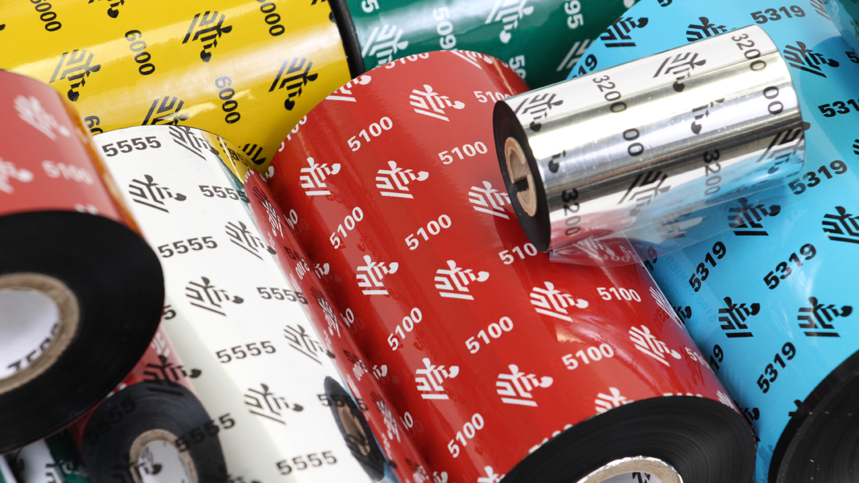Close-up view of a range of various Zebra wax resin ribbons with vibrant yellow, red, white, green, and blue packaging designs labeled with product codes such as 5100, 5555, 5319, and 3200, ideal for various printing needs such as shipping and inventory management and retail tags.